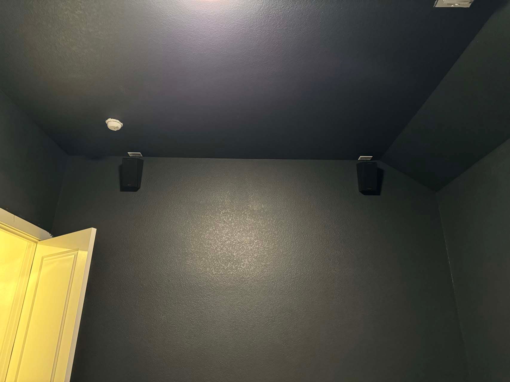 A room with a black ceiling and two speakers on the wall.