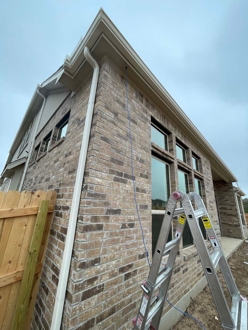 A ladder is sitting on the side of a brick house.