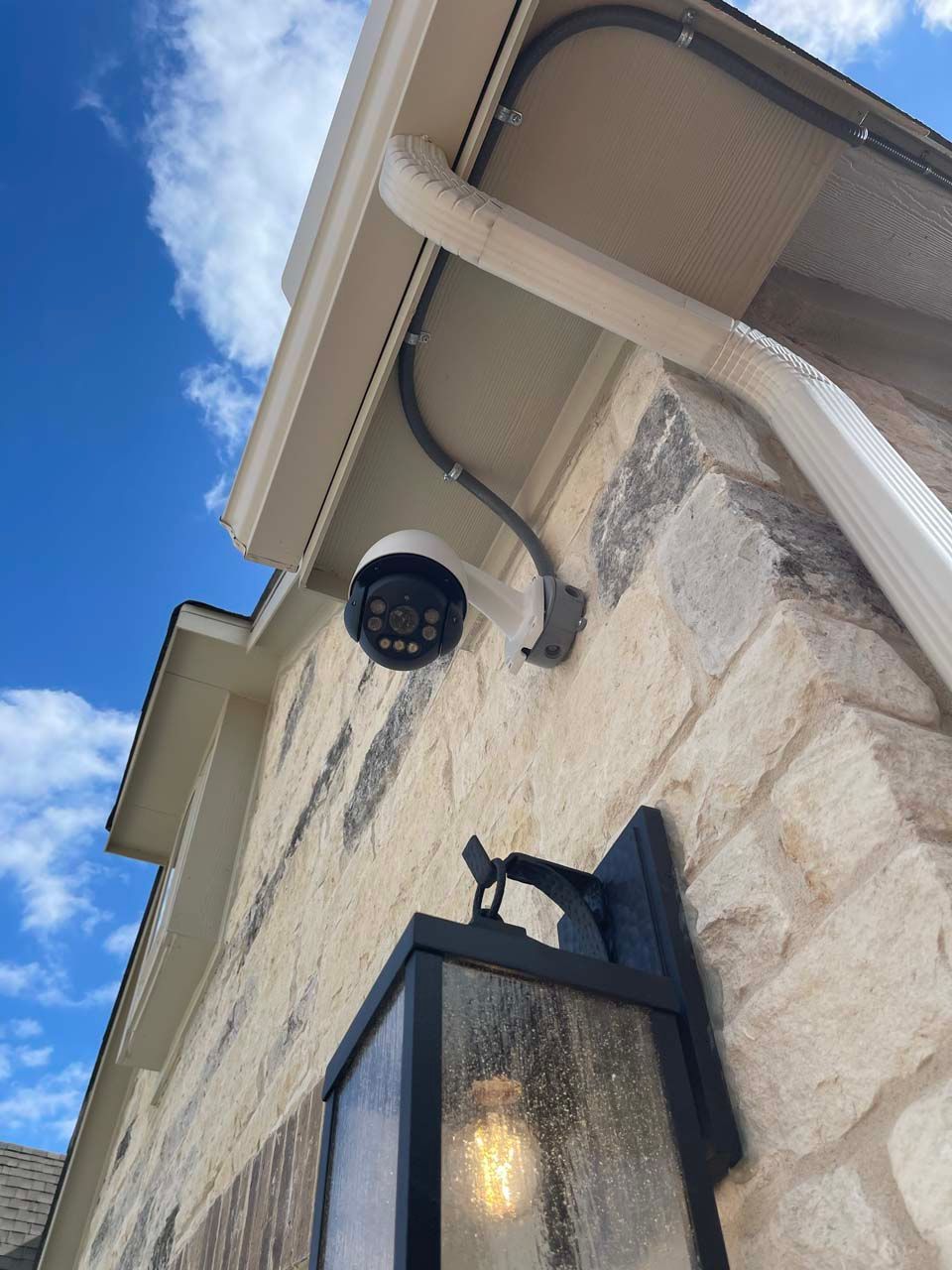 A security camera is mounted on the side of a house.