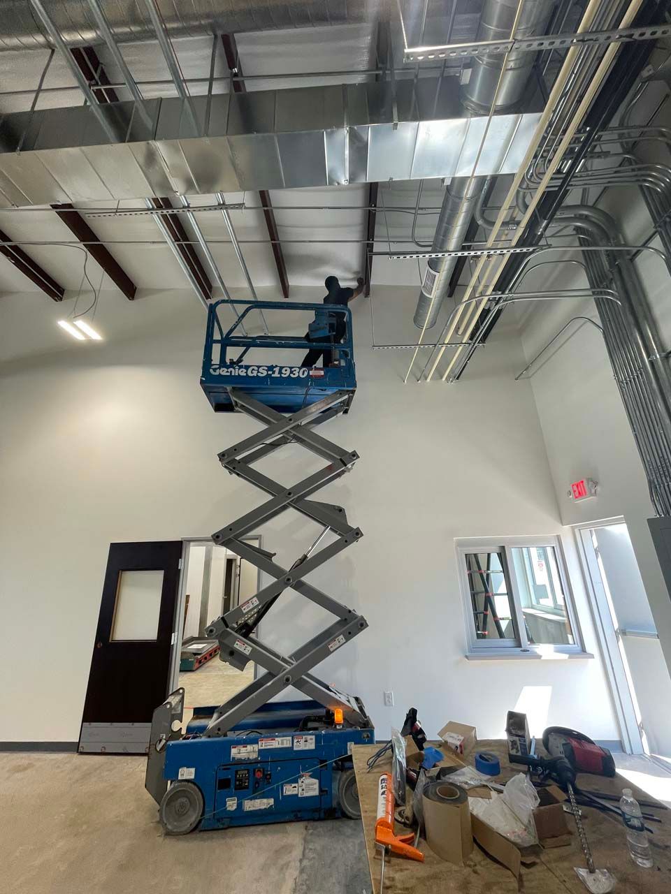 A man is standing on a scissor lift in a room.