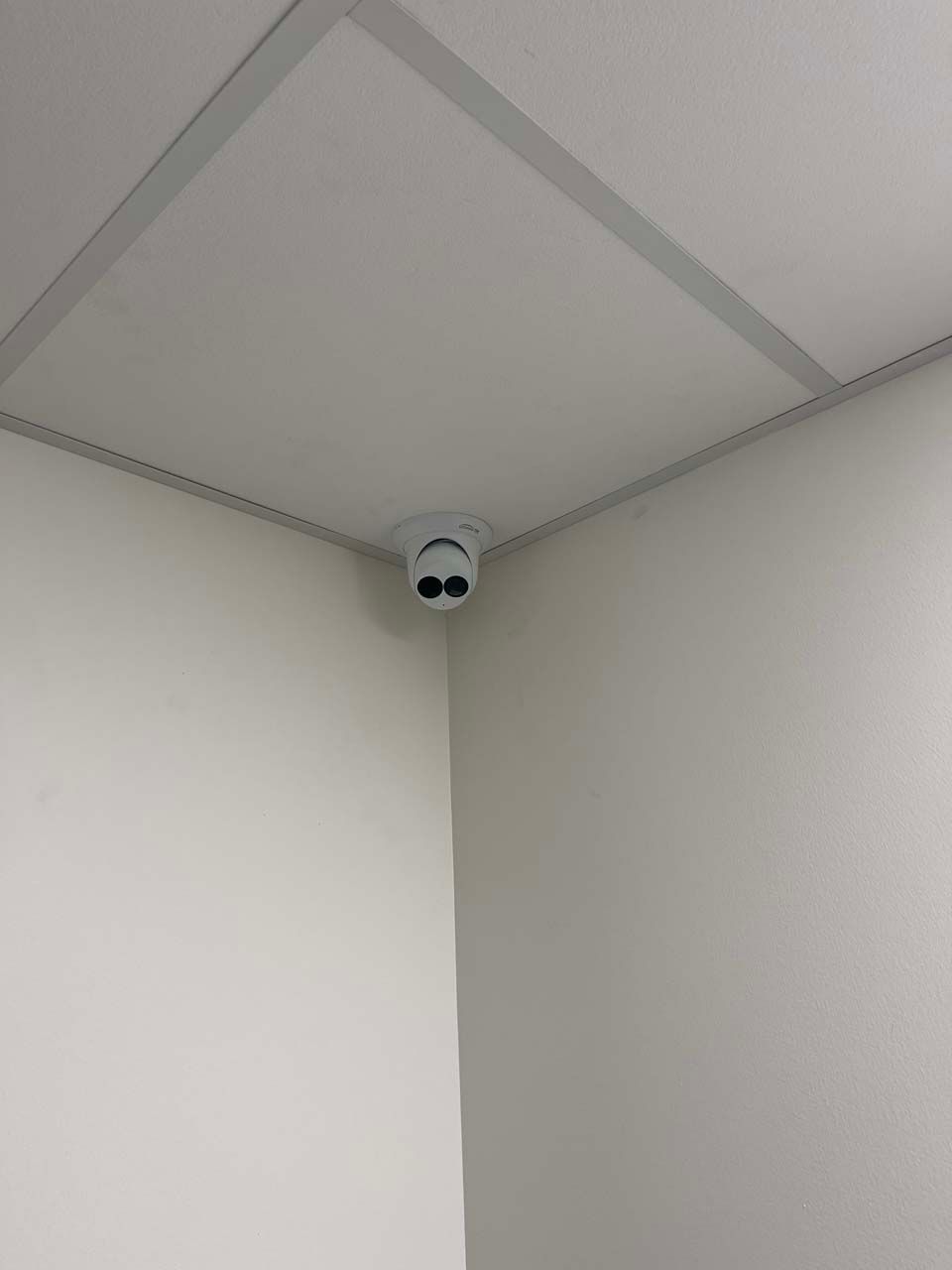 A smoke detector is mounted in the corner of a room.