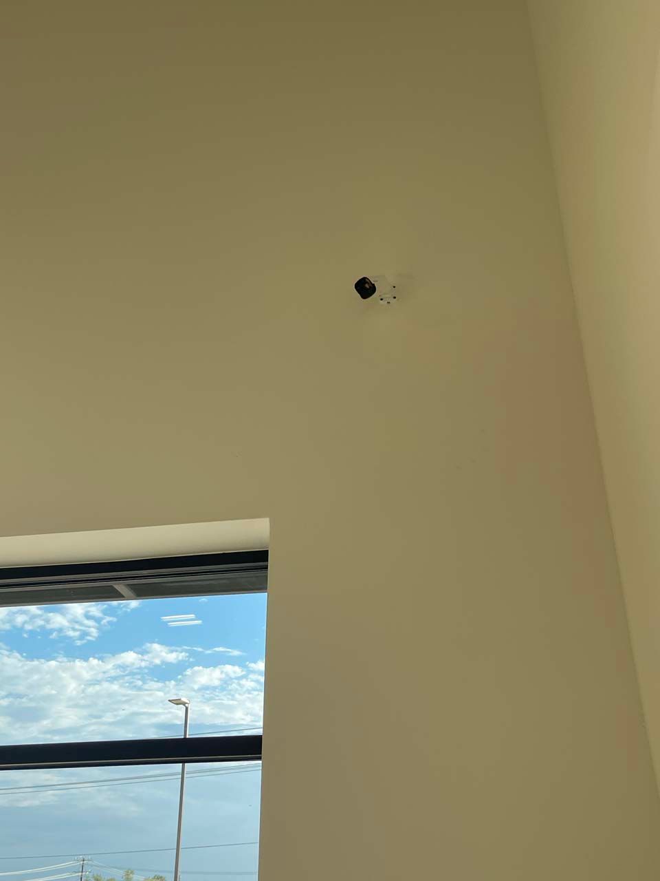 There is a hole in the wall next to a window.