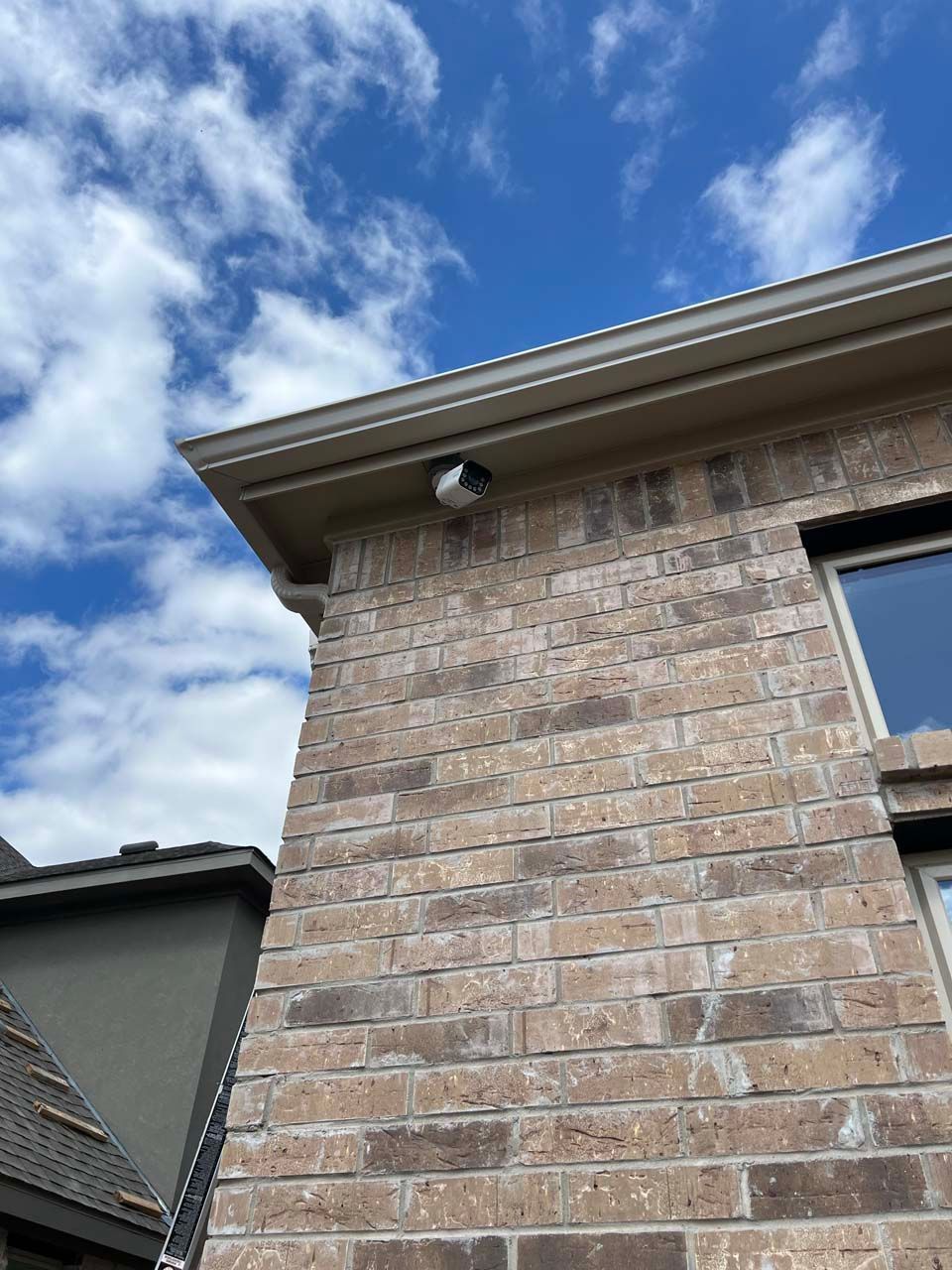 A brick building with a window and a blue sky in the background.