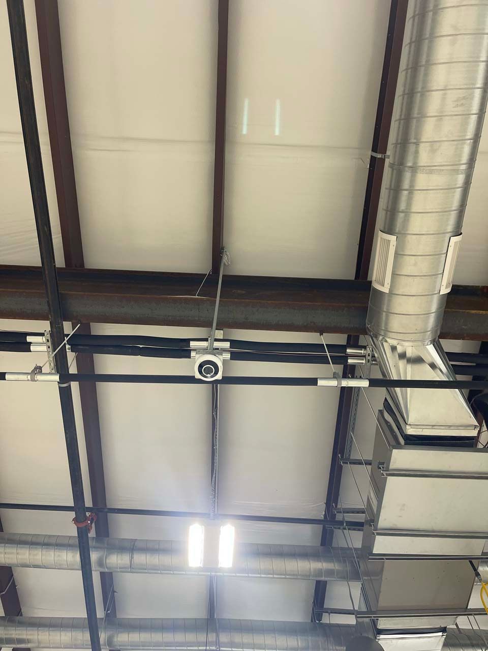 The ceiling of a building with a lot of pipes hanging from it.