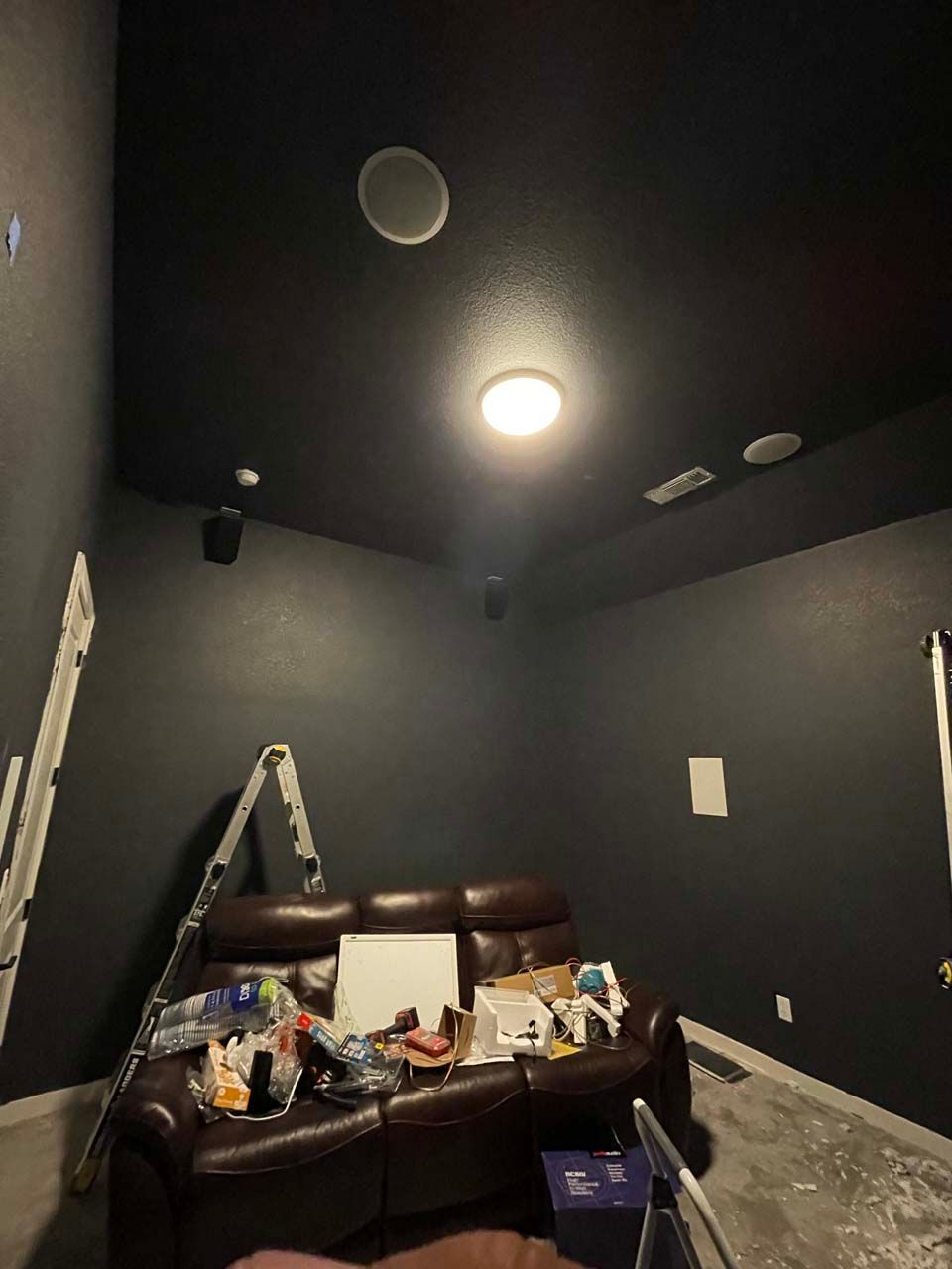 A living room with a couch and a ladder in it.