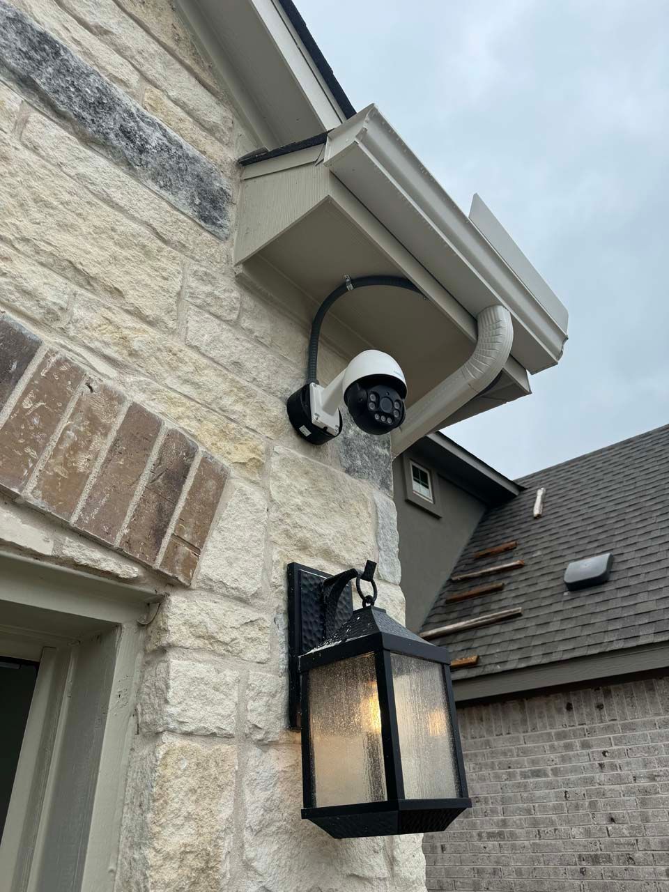 A security camera is mounted on the side of a brick building.