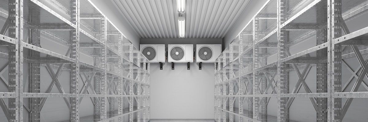 Interior of a cold storage room with stacks of white plastic crates and cooling units.