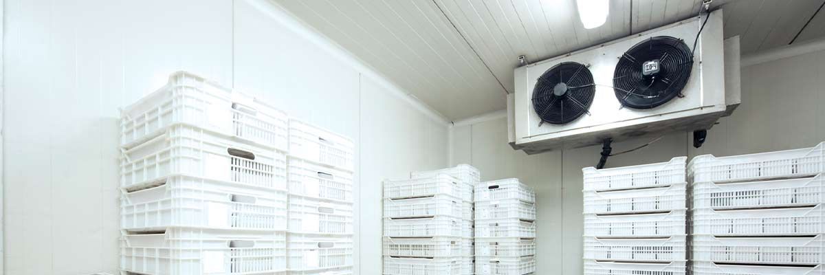 ABC Refrigeration Interior of a cold storage room with stacks of white plastic crates and cooling units.