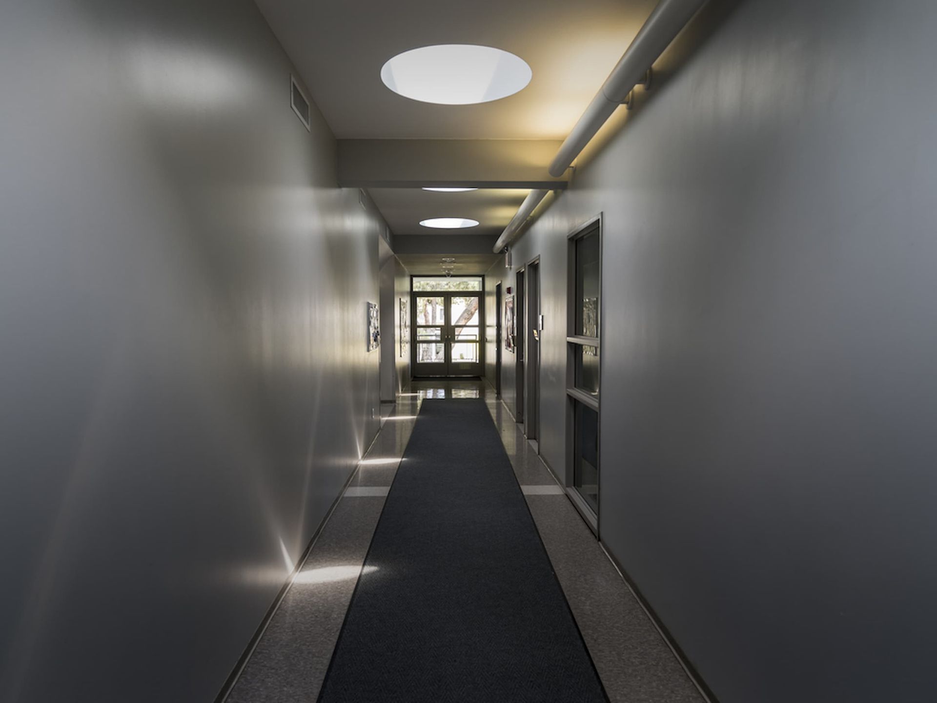 A Long Hallway with A Black Carpet and A Ceiling Light — A Brush With Colour in Pialba, QLD