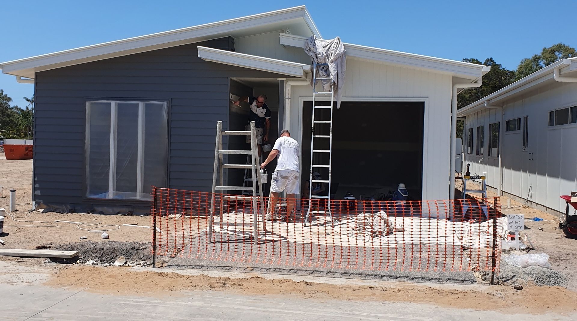 A Man Is Painting A Wall While Standing On A Ladder — A Brush With Colour in Maryborough, QLD
