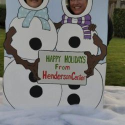 A couple of snowmen holding a sign that says happy holidays from henderson center