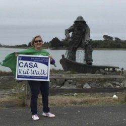 A woman is holding a sign that says casa kid walk
