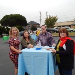 A group of people are standing around a table in a parking lot.