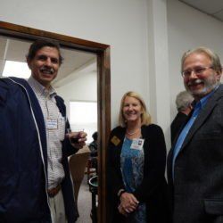 Three people are standing next to each other in a doorway.