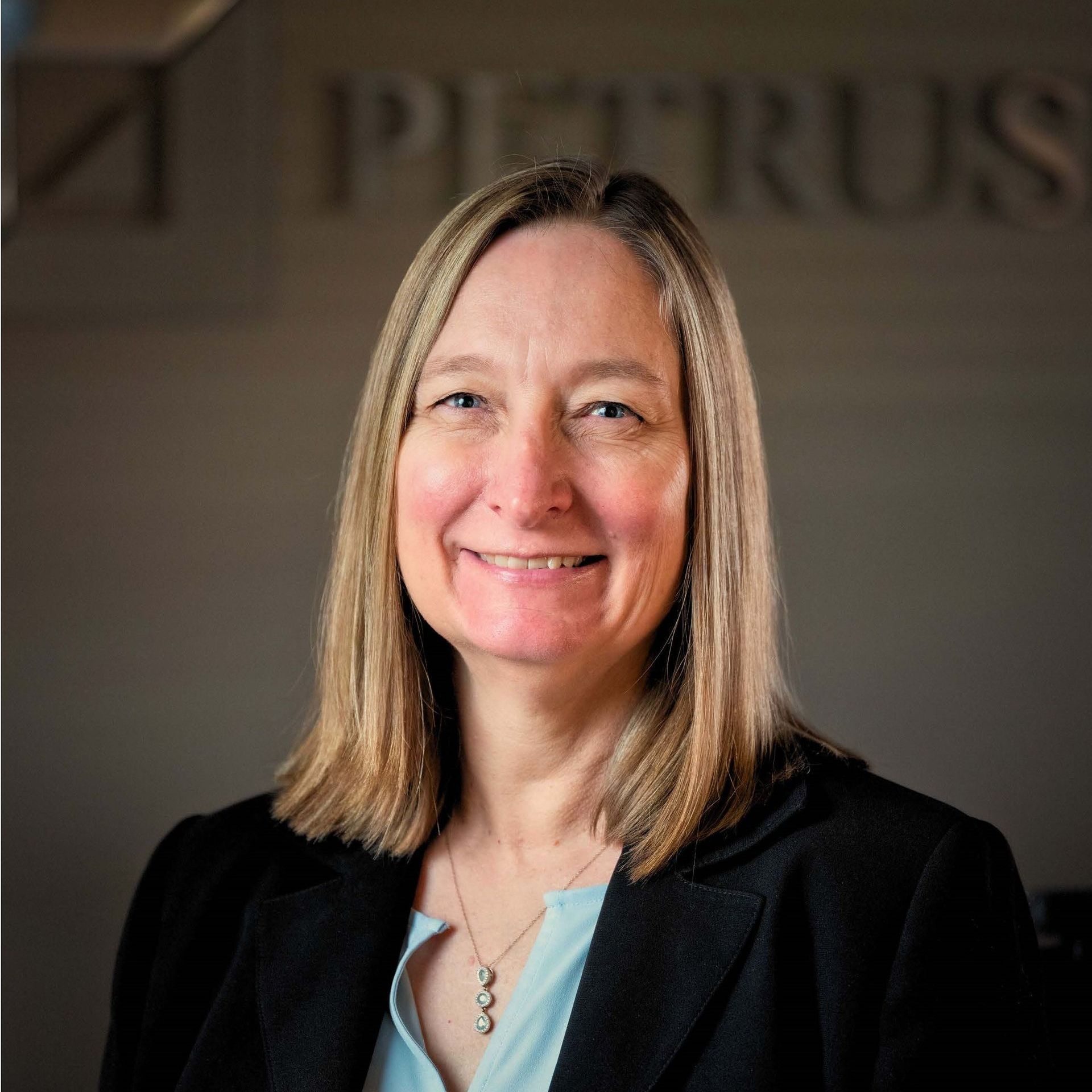 A woman is smiling in front of a petrus sign