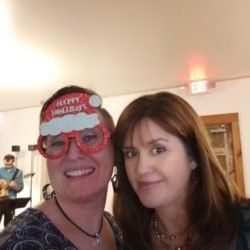 Two women posing for a picture with one wearing a santa hat