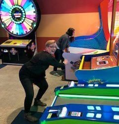 A group of people are playing arcade games in an amusement park.