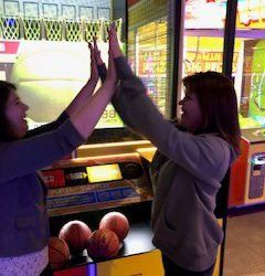 Two women are giving each other a high five in an arcade.
