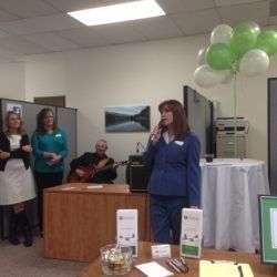 A woman is speaking into a microphone in front of a group of people.