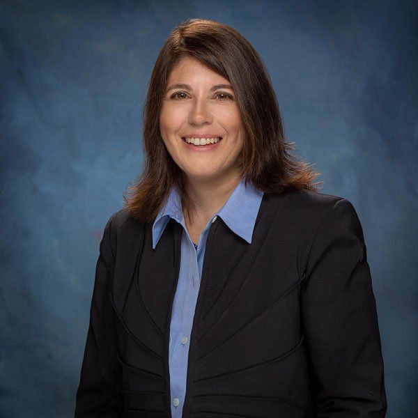 A woman in a suit and blue shirt is smiling for the camera.