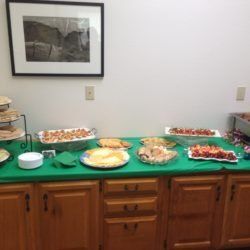 A buffet table with plates of food and a picture on the wall.