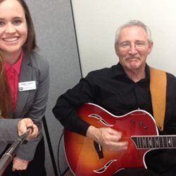 A man is playing a guitar next to a woman