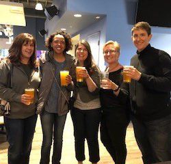 A group of people are standing next to each other holding beer mugs.