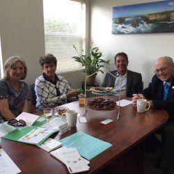 A group of people are sitting around a table with food and drinks.