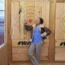 A woman is standing in front of a wooden target.