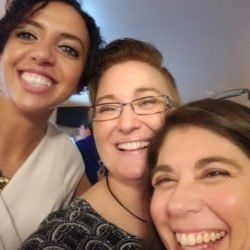 Three women are posing for a picture together and smiling for the camera.
