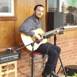 A man is sitting on a stool playing a guitar