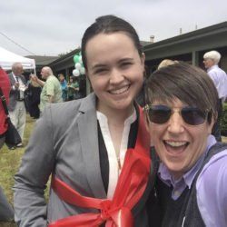 Two women are posing for a picture with a red ribbon around their necks