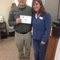 A man and a woman are posing for a picture while the man is holding a certificate.