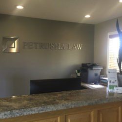A reception desk in a law office with a sign on the wall that says petrusha law.