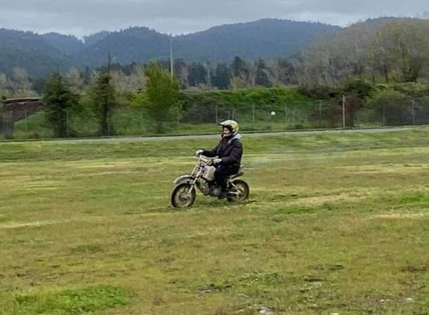 A man is riding a motorcycle through a grassy field.