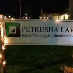 A petrusha law estate planning and administration sign is lit up at night.