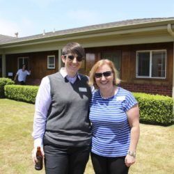 Two women are posing for a picture in front of a house