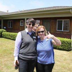 Two women are posing for a picture in front of a house.