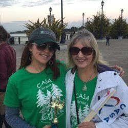 Two women wearing green casa shirts are posing for a picture.