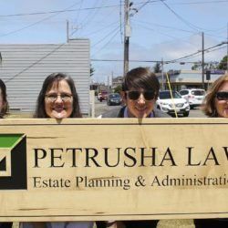 A group of people are holding a sign for petrusha law estate planning and administration.