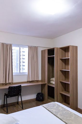 Um quarto com uma cama, escrivaninha, prateleiras e uma janela.-hotel-malibu-inn