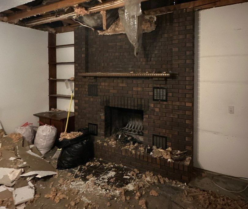 Renovated room with a brick fireplace. Debris and exposed ceiling.