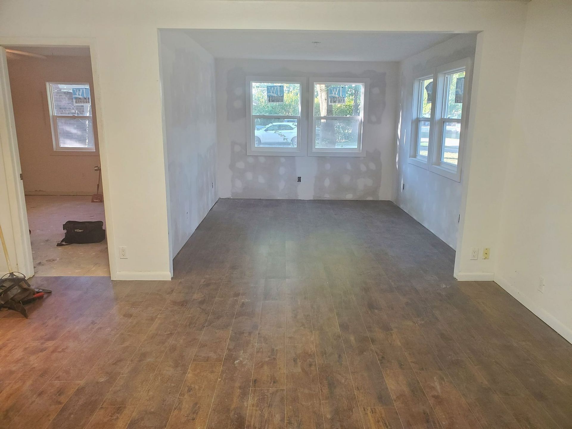 Newly renovated room with wood floors and three windows.