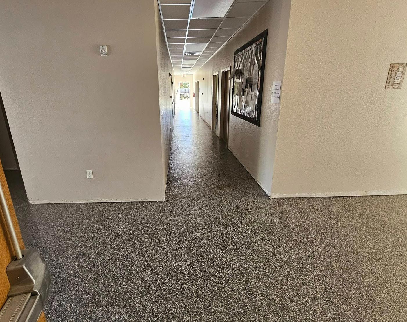 Hallway with epoxy floor, beige walls, and overhead lights.