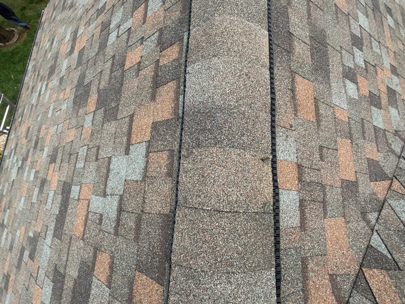 Close-up of a roof's ridge and shingles with various earth-toned colors.