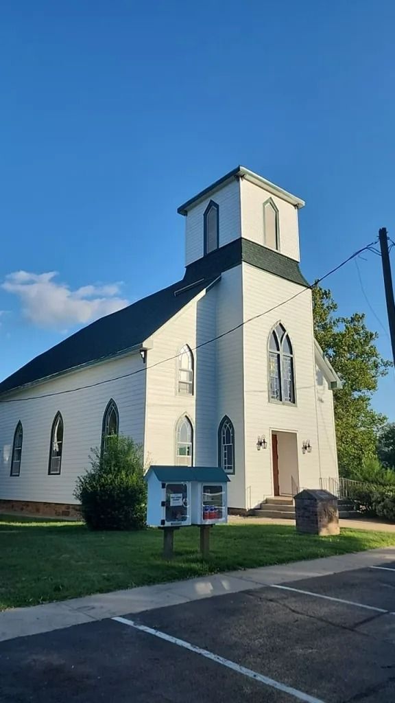 White church with green roof and small tower under a blue sky.