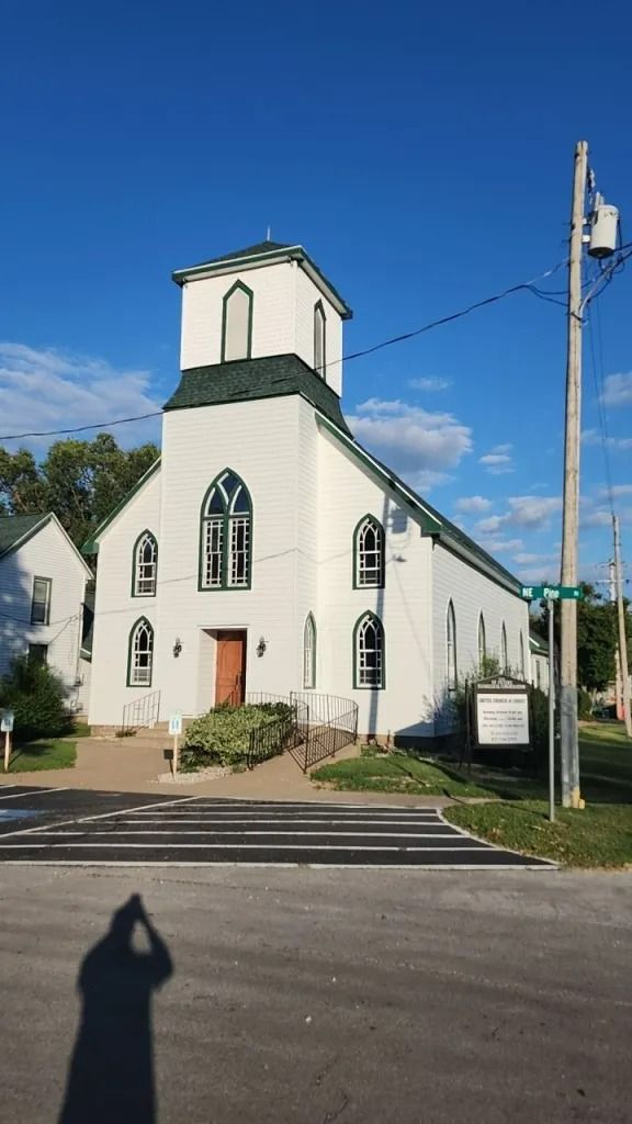 White church building with steeple, green roof, and crosswalk.