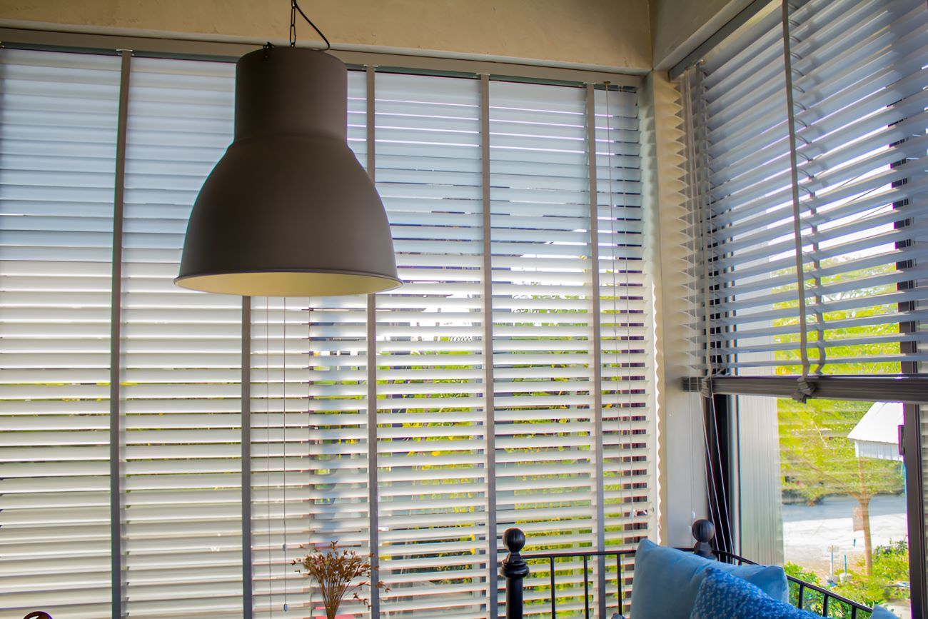 A Living Room With a Bed, Couch, Lamp and Blinds on the Windows — Homestead Blinds in Wodonga, VIC