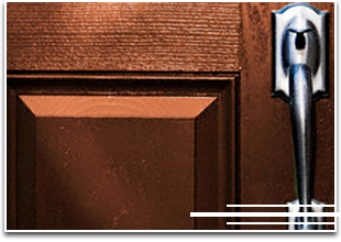 Primer plano de una puerta de madera marrón con tirador plateado.