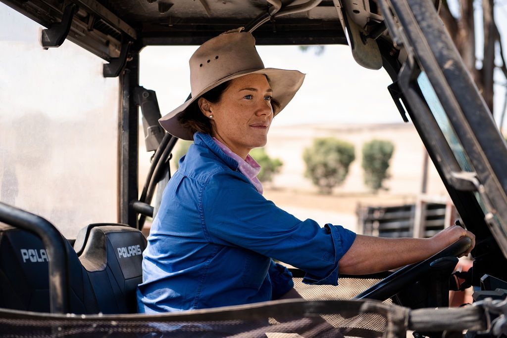 A female farm owner sitting in a 4x4 with an agricultural landscape in the background.